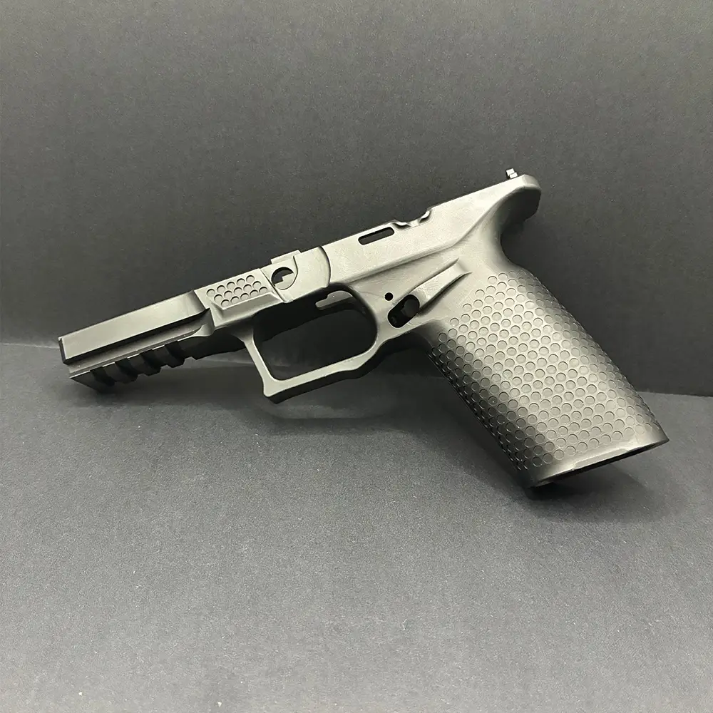 Black precision-machined pistol frame with a textured grip and integrated accessory rail, displayed against a black background.