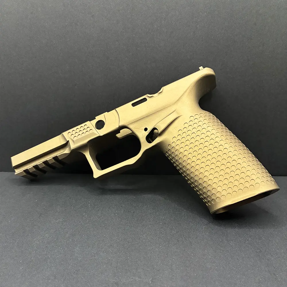 Burnt bronze precision-machined pistol frame with a textured grip and integrated accessory rail, displayed against a black background.