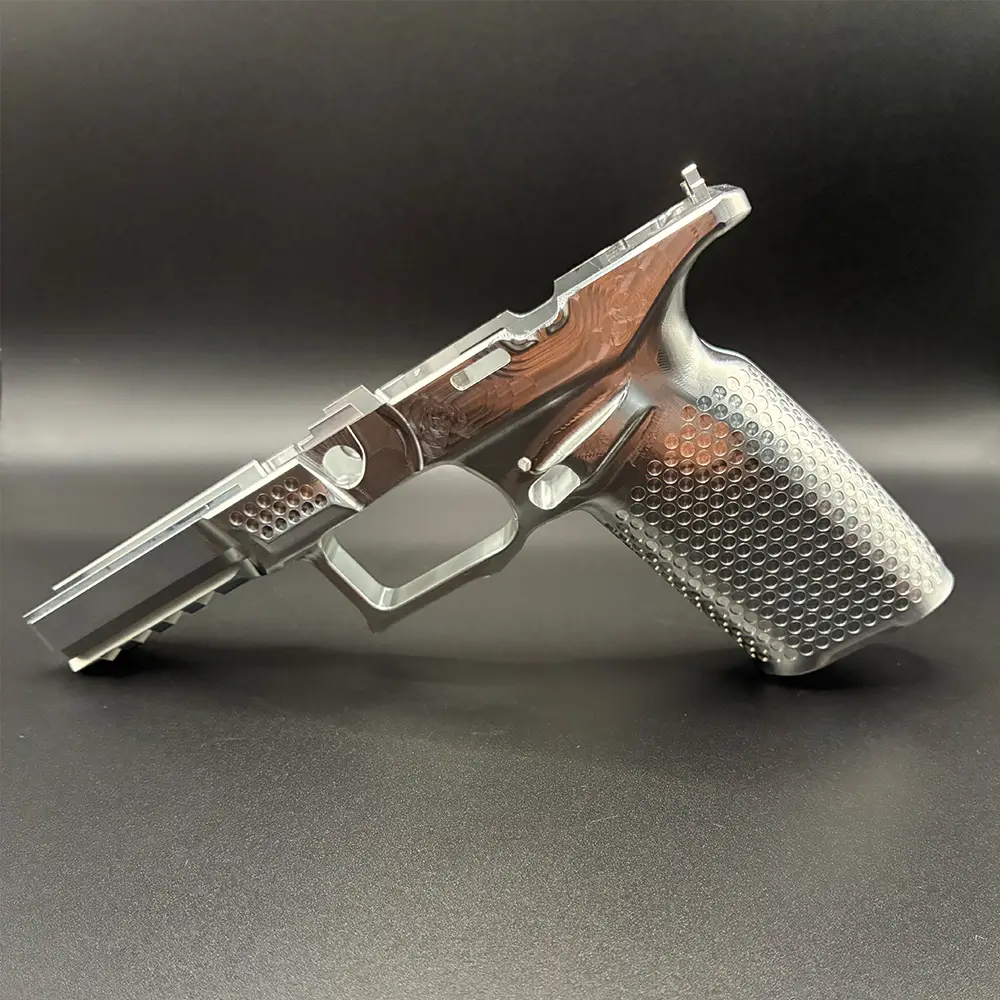 Raw aluminum precision-machined pistol frame with a polished finish, textured grip, and integrated accessory rail, displayed against a black background.
